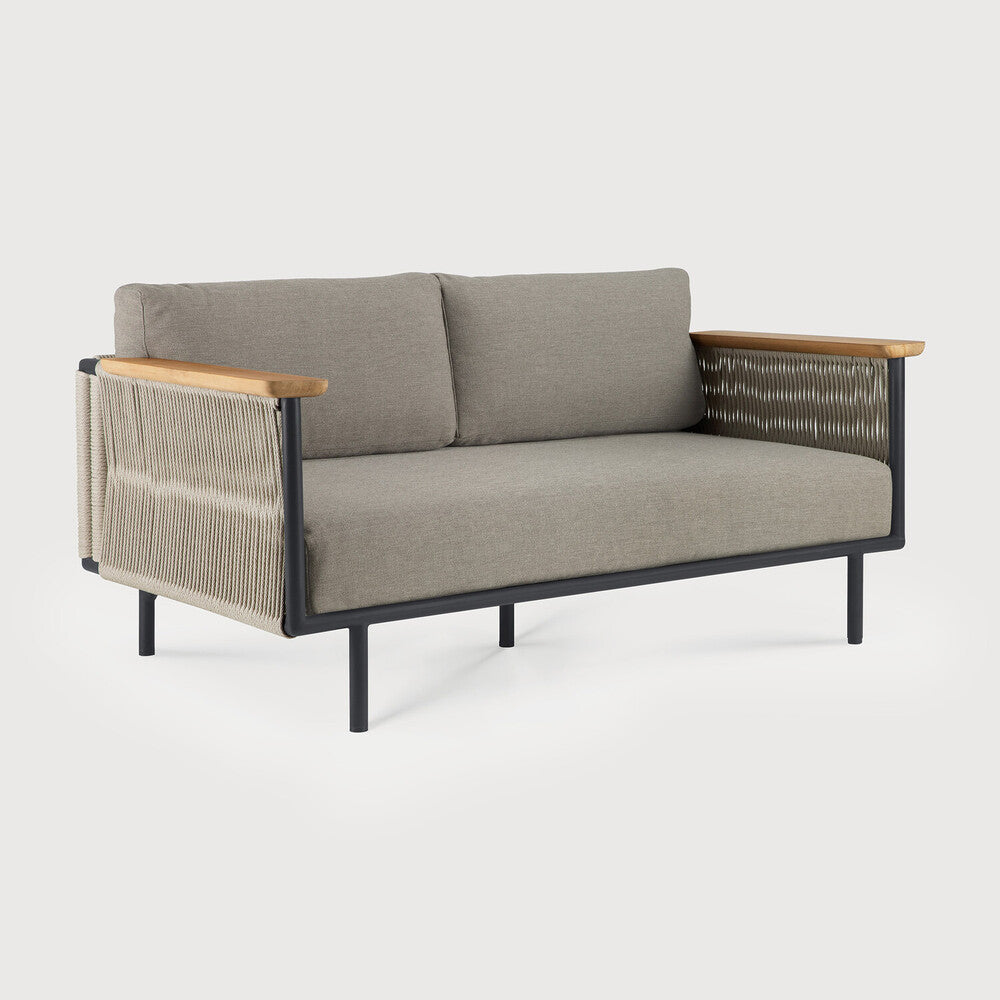 The Corbey Outdoor Sofa by Ethnicraft has light gray cushions, a black metal frame, wooden armrests, and woven rope sides—ideal for crafting an outdoor haven against a plain light background.