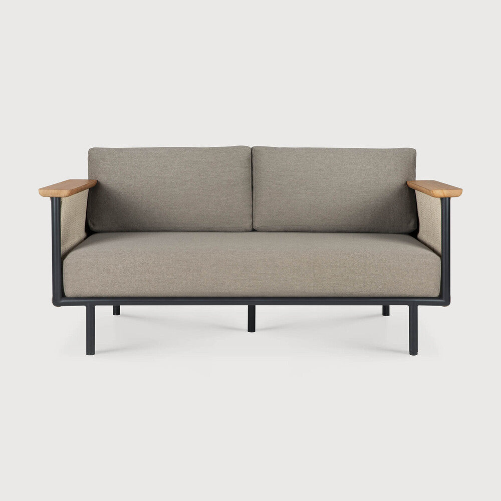 The Corbey Outdoor Sofa by Ethnicraft is a stylish two-seater with grey cushions, a black metal frame, and light wood armrests—perfect for your outdoor space against a white backdrop.
