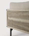Close-up of the Ethnicraft Corbey Outdoor Sofa, showing a beige cushion and woven rope side panel on black metal legs. This stylish piece creates an inviting outdoor haven against a plain white background.