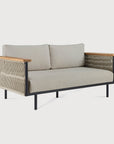 The Ethnicraft Corbey Outdoor Sofa features light beige cushions, a black metal frame, wooden armrests, and rope side detailing—a modern two-seater ideal for your outdoor space, shown here against a white background.