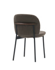 The Solace Dining Chair | Fabric by Wooden Stories is a modern upholstered dining chair with a rounded brown seat and backrest, slim black metal legs, and a wood accent on the upper backrest, shown against a white background.