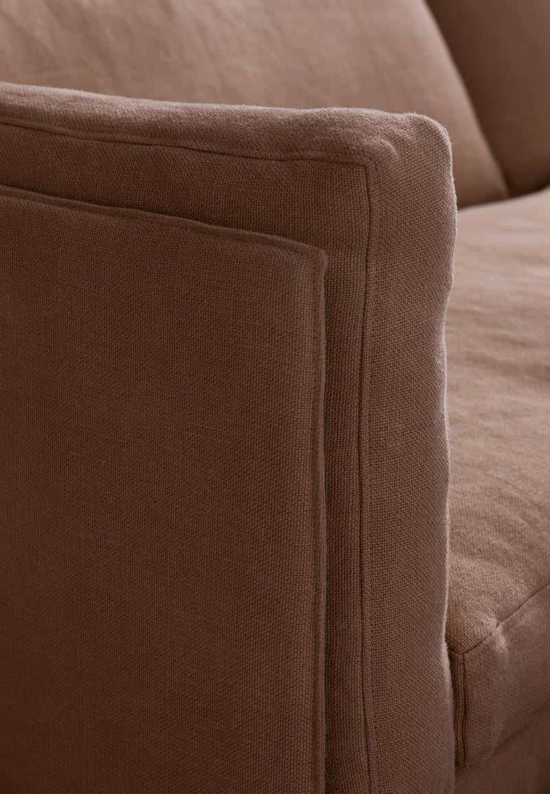 Close-up of the armrest and cushion of the Sonder Sofa | Fabric by Wooden Stories in brown fabric, showcasing its soft texture and precise stitching details.