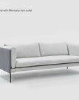 A modern Sonder Sofa | Fabric by Wooden Stories, featuring light gray upholstery, three plush feather-filled cushions, Danish-inspired lines, black metal legs, and armrests. Text in the corner reads: “Sonder 79”, Westlake Diamond with Montana Iron outer, available in-store only.