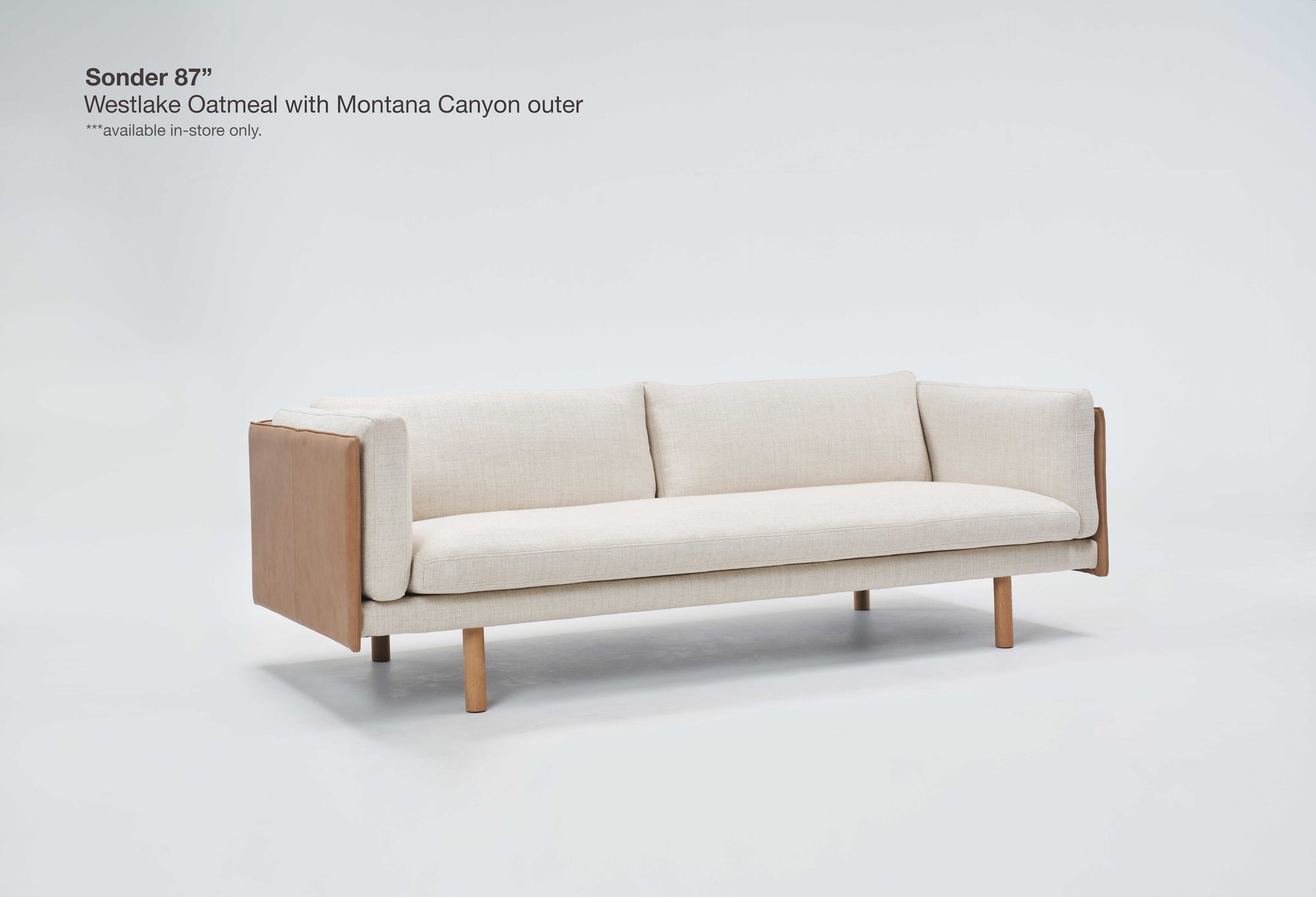 A modern beige three-seat sofa, the Sonder Sofa | Fabric by Wooden Stories, is displayed on a plain white background. With elegant Danish-inspired lines and a sleek linear frame complemented by wooden sides and legs, this design seamlessly blends timeless style with comfort. In the top left corner, text highlights the model name and upholstery details.