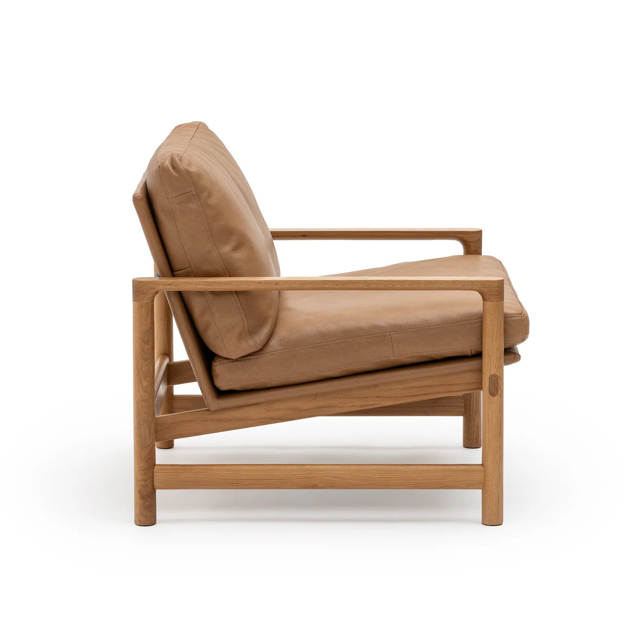 Side view of the Troubadour Lounge Chair | Leather • Light Oak by Wooden Stories, featuring tan leather cushions and a solid light oak frame with clean lines and minimalist, Danish-inspired design against a white background.