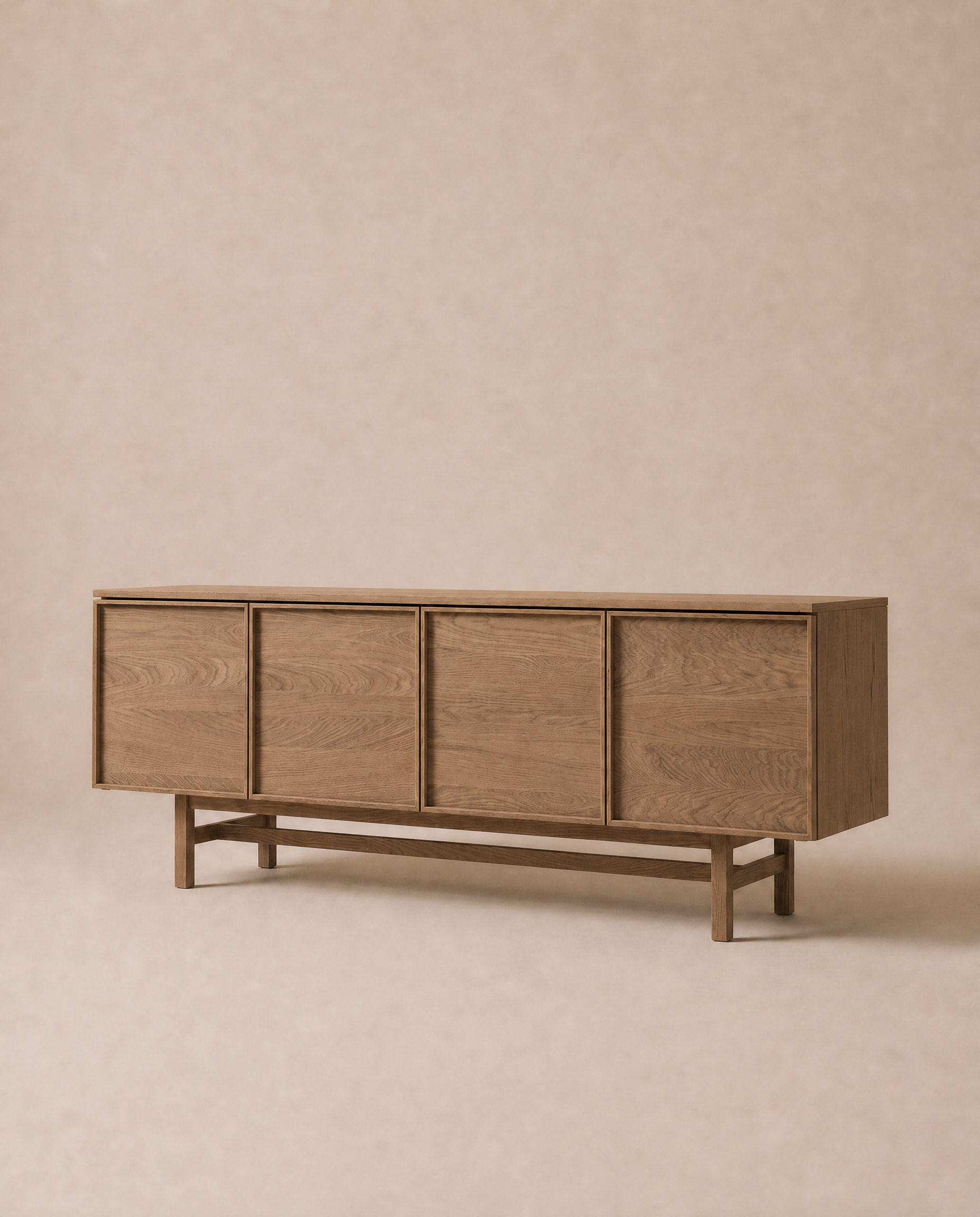 The Wooden Stories Yorke Sideboard, crafted from solid oak, stands against a neutral beige background. It showcases clean lines and a minimalist, mid-century modern look inspired by classic Scandinavian design, with four doors offering ample storage.