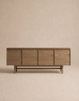 The Wooden Stories Yorke Sideboard features four panel doors and a minimalist design, showcased against a beige background. Its elegant Scandinavian-inspired style is highlighted by the visible grain of solid oak, while a simple rectangular base provides sturdy support.